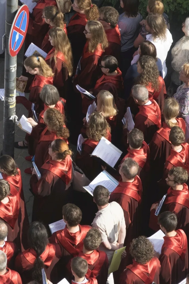 Choir members in red robes holding sheet music seen from above
